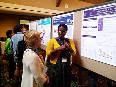 Student standing in front of research poster speaking to audience